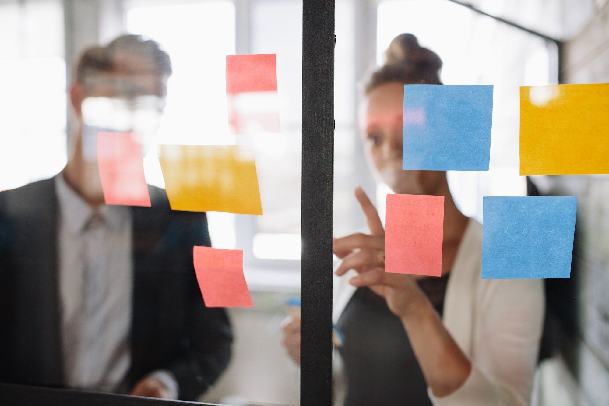Business woman pointing at sticky note to male colleague